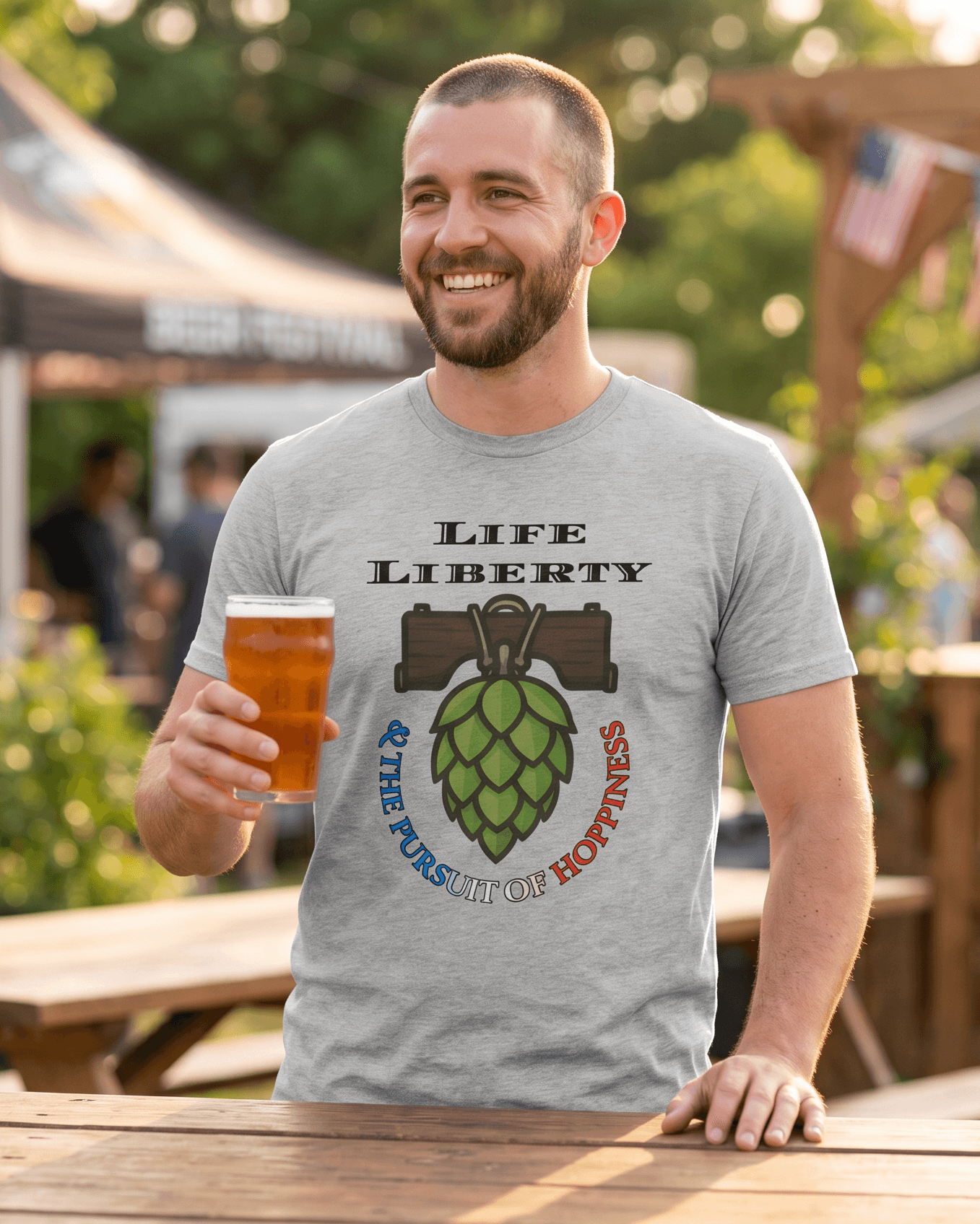 Man wearing funny beer-themed graphic tee with hop design, holding beer at outdoor festival