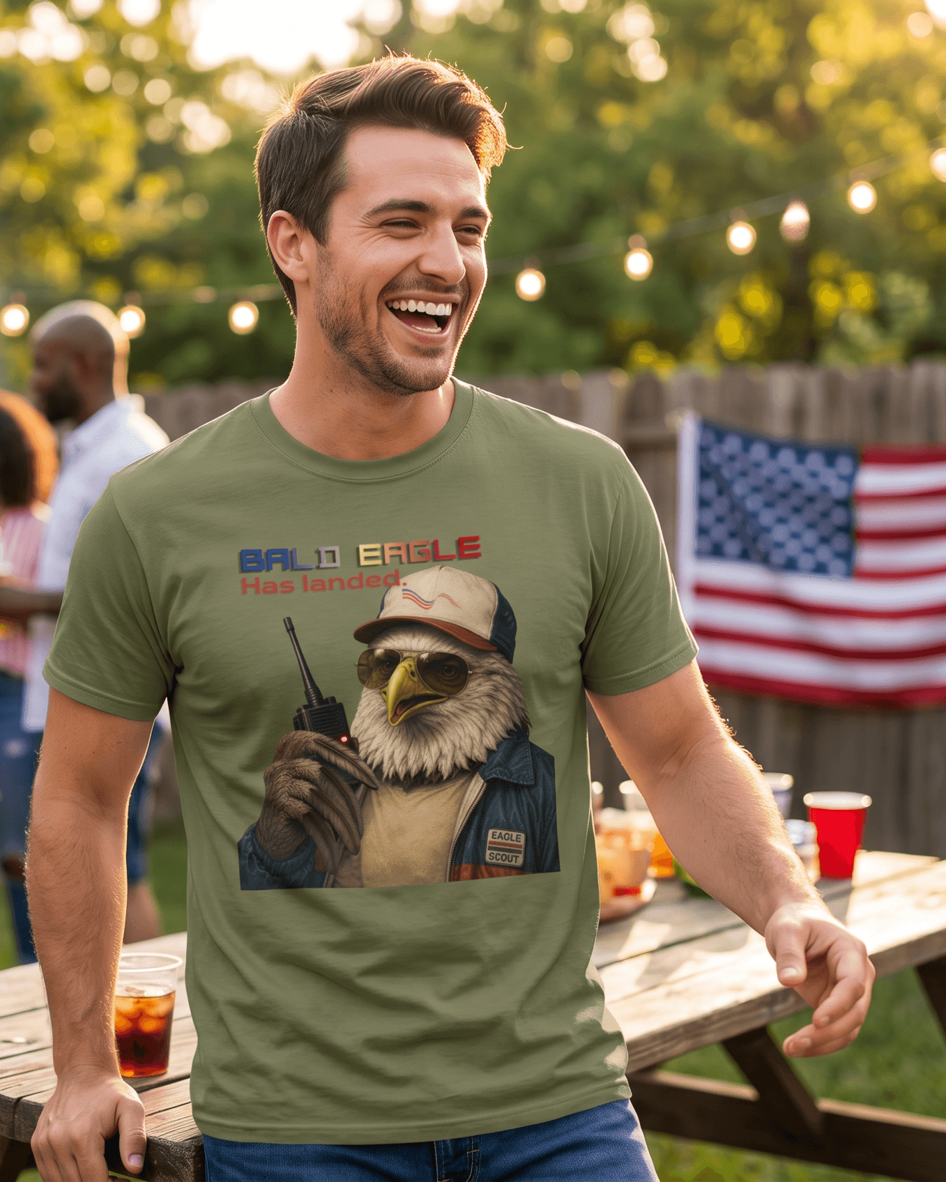 Man wearing a green t-shirt with an eagle graphic at a casual outdoor gathering.