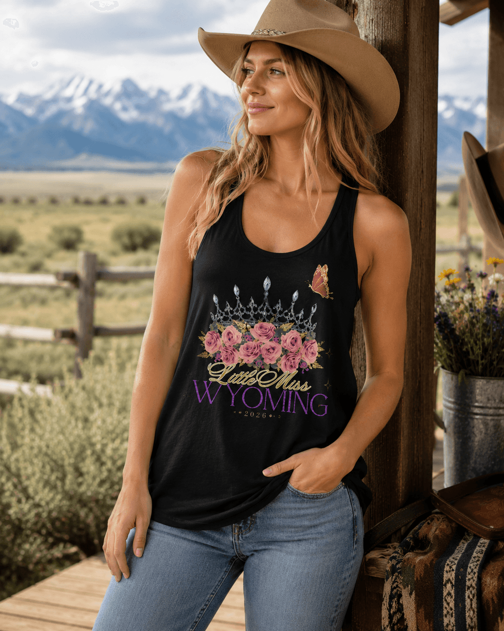 Woman in cowboy hat wearing black 'Little Miss Wyoming 2026' tank top with crown, roses, and butterfly design