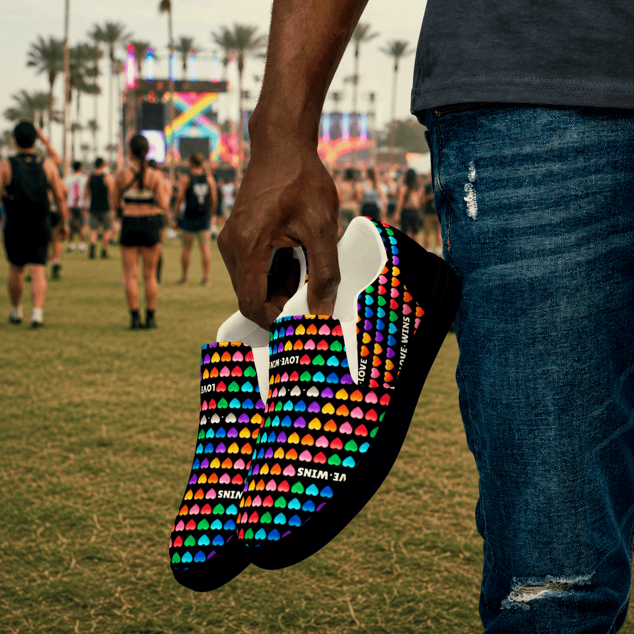 Rainbow heart-patterned shoes with 'Love Wins' text, held at a vibrant festival