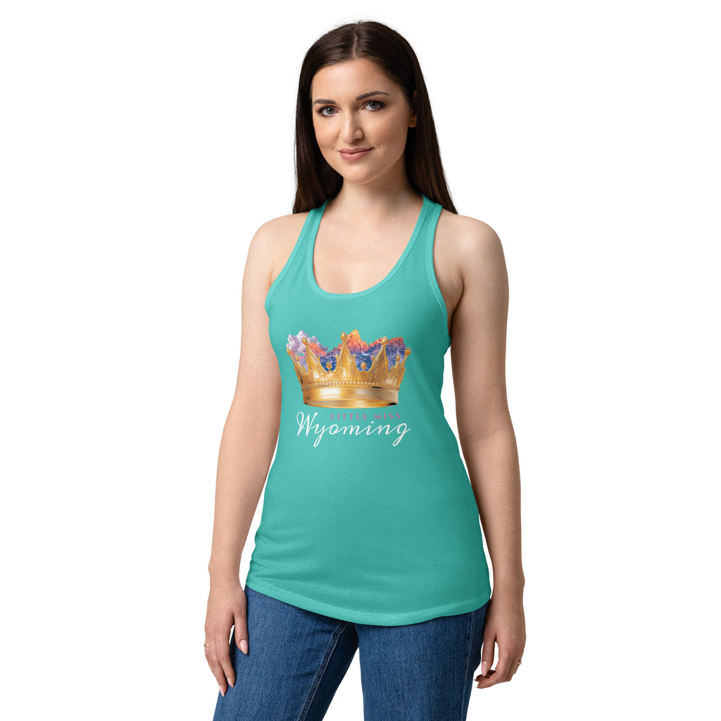 A woman modeling a teal racerback tank top with a graphic of a gold crown with colorful floral accents and the word 'Wyoming' in white script, paired with blue jeans against a plain white background.